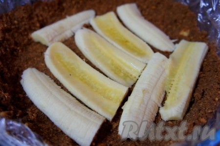 Банан разрезать вдоль, уложить на основу из печенья.