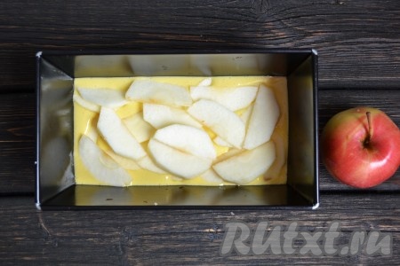 Вливаем половину теста в форму для выпечки (при желании форму для выпечки можно смазать маслом, чтобы выпечка не пристала к форме) и выкладываем половину яблок.
