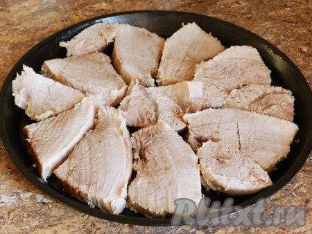 Когда свинина сварится, вынуть ее из бульона, немного остудить и нарезать на порционные кусочки. Форму для выпечки слегка смазать маслом. Выложить мясо.
