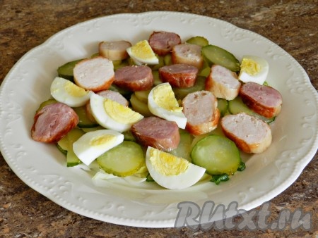 Очищенные яйца и колбаски нарезать, добавить в салат к картошке, соленым огурцам и луку.
