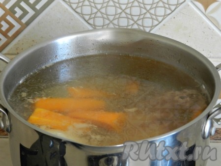 Когда вода закипит, снять тщательно всю пену. Добавить луковицу, крупно нарезанную морковь и варить бульон на самом медленном огне в течение 40-45 минут, до готовности мяса.
