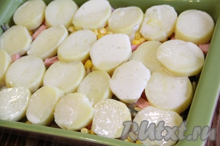 Поверх колбасной начинки выложить кружочки картошки в один слой. Вылить получившуюся яично-молочную смесь поверх картофеля.