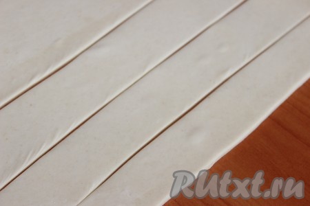 Размороженное тесто слегка раскатать и разрезать на тонкие полоски шириной, примерно, по 2-2,5 сантиметра.
