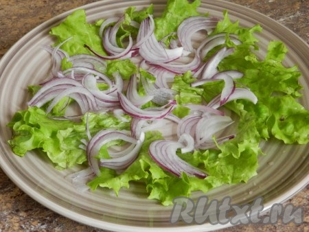 В тарелку нарвать руками листья салата. Добавить лук.