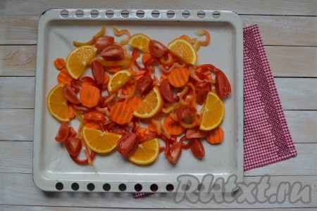 Половину лимона и половину апельсина нарезать тонкими полукольцами. Перцы вымыть, удалить плодоножки и семена, нарезать соломкой. Очистить морковь и нарезать тонкими колечками. Вымыть помидоры и разрезать на 4 части. Все подготовленные овощи и цитрусовые выложить на противень (при желании противень можно смазать растительным маслом).
