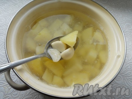 Очищенный картофель нарезать кубиками, залить водой. Довести воду до кипения, убрать пену, посолить по вкусу. Добавить к картофелю очищенный и разрезанный на 2 части чеснок.
