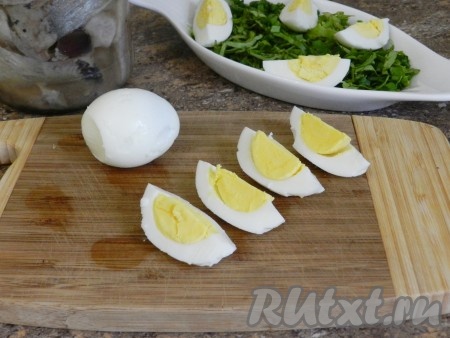 Яйца нарезать четвертинками. В салатник выложить нарезанную зелень, яйца и селедку.
