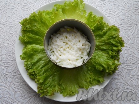 На тарелке разместить салатные листья, а сам салат выкладывать слоями с помощью кулинарного кольца. Можно салат готовить и в салатнике. Первым слоем выложить половину белков + майонез.
