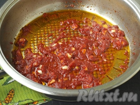 Когда лук замаринуется, можно готовить заправку для салата. В сковороде хорошо разогреть масло и выложить томатную пасту, обжаривать 4-5 минут. Затем чеснок, нарезанный кубиками, добавить в сковороду, жарить ещё пару минут, иногда помешивая.