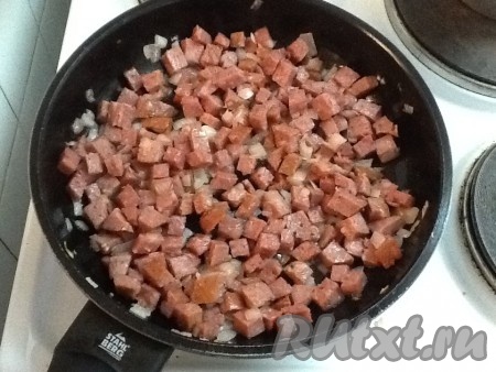 Копченую колбасу нарезать и добавить на сковородку к луку.