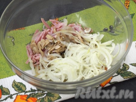 Пластинками нарезать маринованные грибы, добавить их вместе с луком в салат из ветчины и маринованных огурцов.
