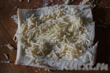 На каждый раскатанный кусочек тостового хлеба выложить кусочек сливочного масла и натертый сыр.
