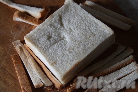 Хлеб для тостов сложить стопочкой и отрезать корочку.