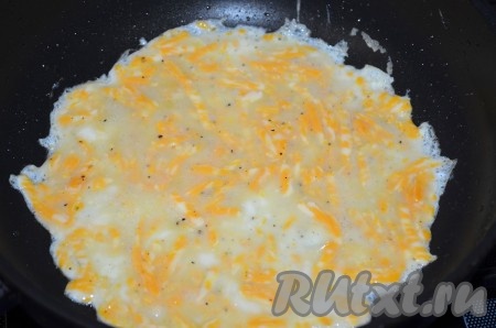В сковороде диаметром 20 сантиметров разогреть немного подсолнечного масла, вылить яичную смесь, распределить по дну. Жарить яичный блинчик до золотистого цвета с одной стороны на небольшом огне.