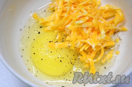 В миску разбить 1 яйцо, добавить половину натёртого сыра, посолить и поперчить по вкусу, взбить вилкой.