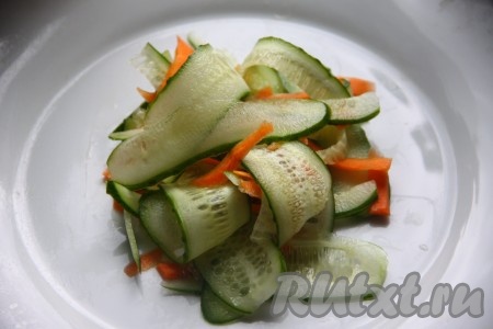 Огурец и очищенную морковь нарезать с помощью ножа для чистки картофеля - тонкими слайсами. Выложить овощи в тарелку и приготовить заправку.