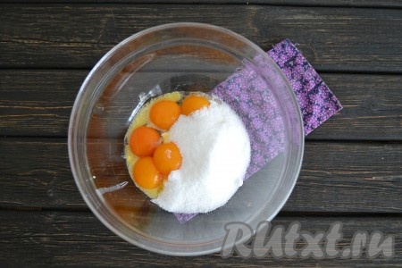 К маслу добавить желтки куриных яиц (белки понадобятся позже, для приготовления глазури) и всыпать оставшийся сахар.
