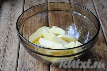 Нарезать картофель крупными дольками. Сложить его в миску, которая подходит для использования в микроволновой печи. 
