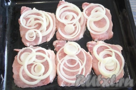 Выложить лук на кусочки свинины.