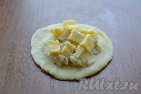 Каждый кусочек раскатать в небольшую тонкую лепешку. В центр лепешки поместить 1 столовую ложку картофельной начинки, сверху картофеля выложить небольшие кубики твердого сыра.