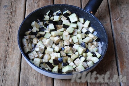 В сковороду налить небольшое количество растительного масла и отправить на огонь. Когда масло разогреется, выложить лук и баклажаны, перемешать. 