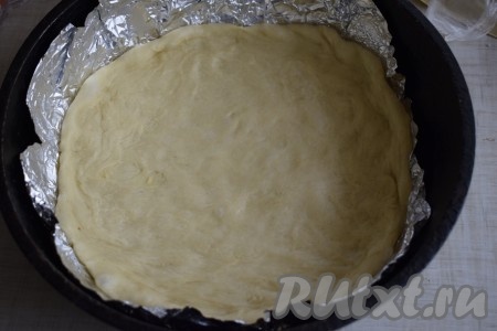 Приготовить дрожжевое тесто для пирога и оставить его для подъема на 1 час. Готовое тесто обмять и выложить в форму для выпечки, застеленную пергаментом или фольгой.