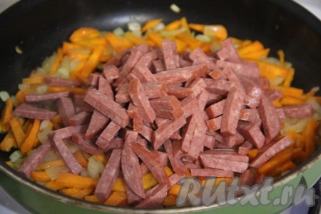 Колбасу нарезать на тонкие брусочки и добавить в сковороду к морковке с луком. Обжарить в течение 5 минут, помешивая.
