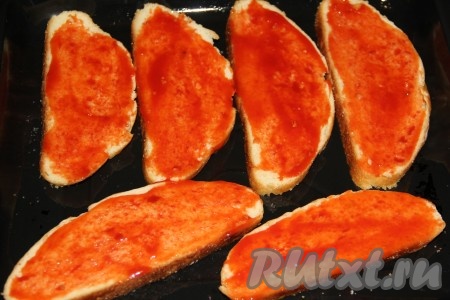 Противень смазать растительным маслом, выложить кусочки хлеба на противень и смазать их кетчупом.