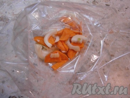 Морковку и лук очистить. В пакет для запекания поместить нарезанный кольцами или полукольцами репчатый лук и нарезанную кусочками морковь.
