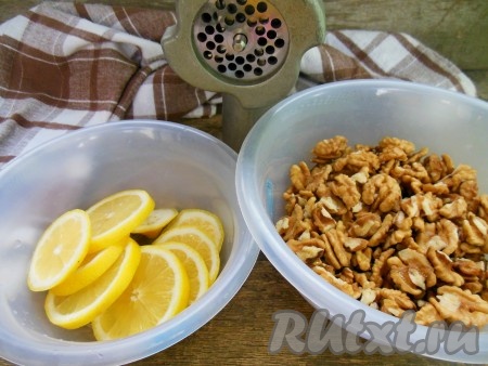 Лимон залейте горячей водой, оставьте на 3-5 минут. Затем воду слейте, лимон хорошо промойте, нарежьте на колечки, удалите косточки. Грецкие орехи и лимон пропустите через мясорубку.