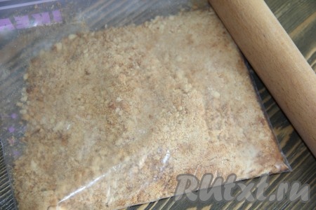 Печенье поместить в плотный пакет и измельчить с помощью скалки в крошку.
