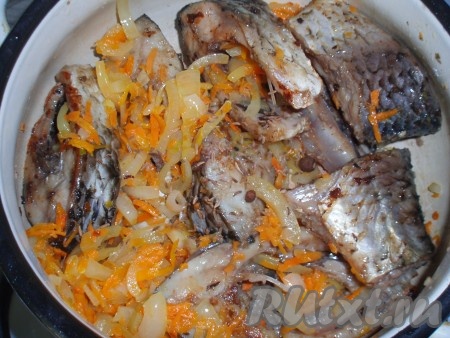 Обжаренные овощи добавить к рыбе. Туда же добавить зубчики чеснока, нарезанные дольками, тмин и горошины черного и душистого перца.
