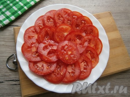 Лук и чеснок очистить. ​​​​​​Твёрдые, плотные помидоры нарезать острым ножом на тонкие (толщиной 3-5 миллиметров) кружочки, выложить их на плоскую тарелку в один слой, чуть посолить.