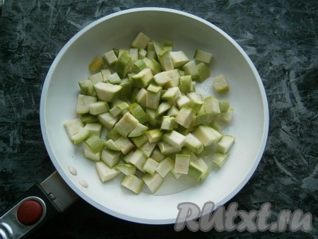 Нарезать кабачки на кубики размером около 1 сантиметра, выложить в сковороду, влить растительное масло.