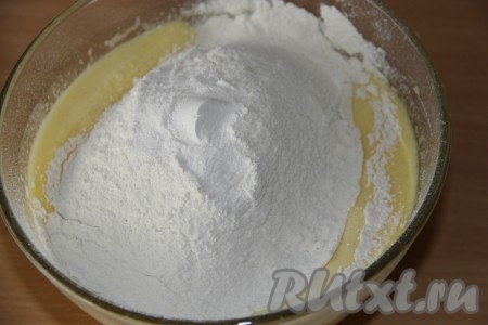 Влить растопленное масло в яичную массу и взбить миксером в течение 1 минуты. Всыпать просеянную пшеничную муку и разрыхлитель.
