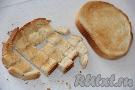 Белый хлеб поджарить в тостере (можно хлеб нарезать на кубики и поджарить с двух сторон на сухой сковороде), затем слегка остудить и нарезать на кубики.
