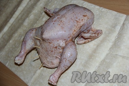 Выложить курицу на лист лаваша. Завернуть лаваш на курицу с двух сторон, а затем полностью завернуть тушку в лаваш.
