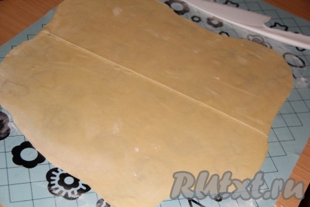 На столе (или на силиконовом коврике), присыпанном мукой, раскатать тесто тонко в прямоугольный пласт. Раскатанное тесто разрезать на две части.
