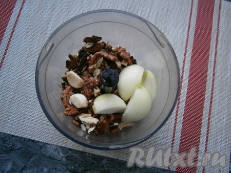 Ядра грецких орехов поместить в чашу блендера. Сюда же выложить очищенный и разрезанный на части лук, а также очищенные зубчики чеснока.