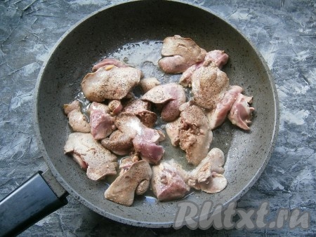 В сковороду с оставшимся растительным маслом поместить куриную печёнку, разрезанную на 2 части, посолить её и поперчить.
