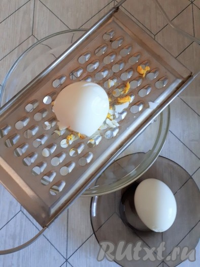 Яйца для салата сварить вкрутую, охладить. Охлажденные яйца почистить, натереть на крупной тёрке, выложить на дно салатницы.
