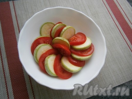 В подходящую глубокую тарелку (или миску), которую смазать растительным маслом, выложить кабачки с помидорами, чередуя их.
