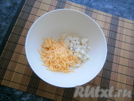 Сыр натереть на средней тёрке, выложить в тарелку, добавить мелко нарезанное варёное яйцо. 