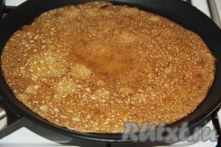 Выпекать яблочный блинчик на среднем огне с двух сторон до золотистого цвета, затем переложить на тарелку. Периодически перемешивая оставшееся тесто, постепенно пожарить все блины.