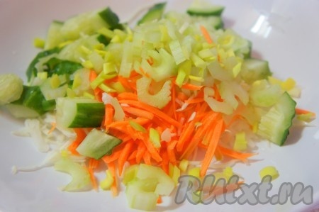 Огурец крупно нарезать, сельдерей очистить и нарезать тонкими пластинками, добавить мелко нарезанный зеленый лук. Добавить нарезанные овощи к капусте и моркови.