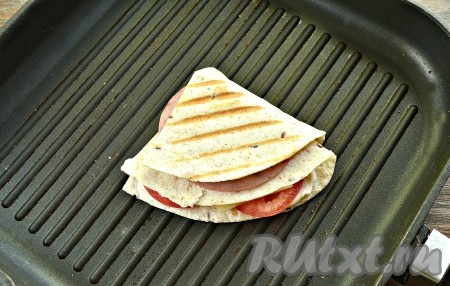 Подрумяниваем сэндвич из тортильи на разогретой сухой сковороде гриль с двух сторон, буквально 1-2 минуты, на среднем огне (до расплавления сыра внутри).