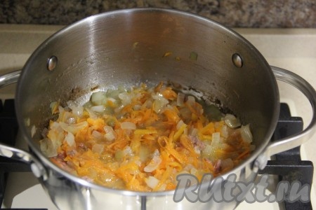 Затем в кастрюлю с луком, обжаренным в жире, выложить очищенную и натёртую морковку, перемешать. Обжаривать овощи, иногда помешивая, 4-5 минут.