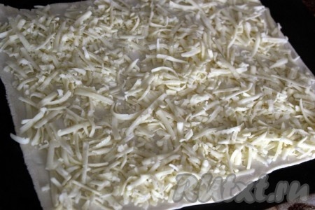 Слоёное тесто раскатать в тонкий пласт (удобно это сделать на силиконовом коврике, который потом поможет и свернуть рулет) и посыпать тертым сыром.