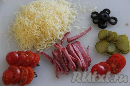Натереть на мелкой тёрке сыр. Колбаску нарезать на брусочки, огурчик и помидоры - на кружочки, маслины без косточек - на колечки.