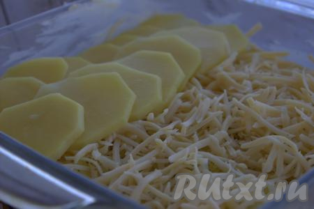 Сыр натереть на тёрке среднего размера. Часть сыра распределить по всей поверхности картошки, выложенной в форму. Поверх сыра выложить внахлёст (как на фото) оставшуюся картошку, ещё раз приправить и слегка посолить.